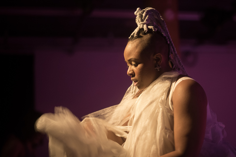 A side profile of Taja Lindley wearing a gauzy white costume